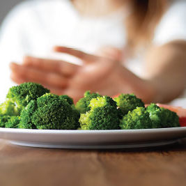 A person rejects a plate of broccoli and tomatoes