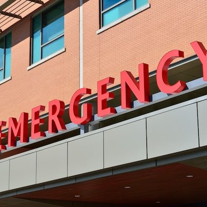 The imposing, red "EMERGENCY" sign at the entrance to a hospital