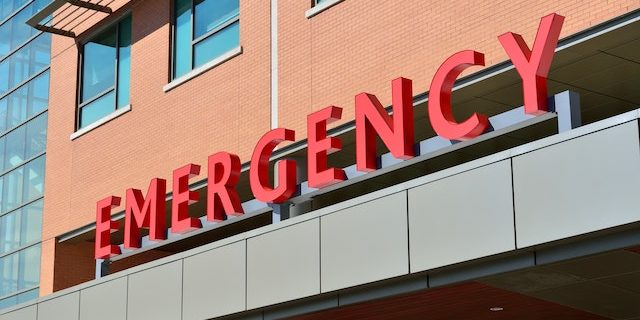 The imposing, red "EMERGENCY" sign at the entrance to a hospital