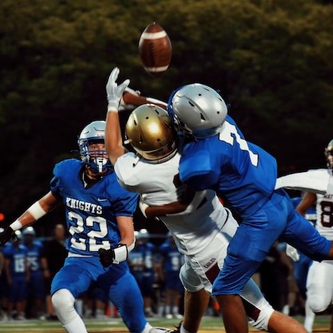 Two football players compete to catch a forward pass