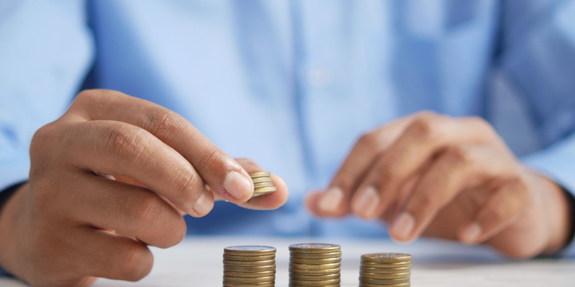A person stacks coins on a table