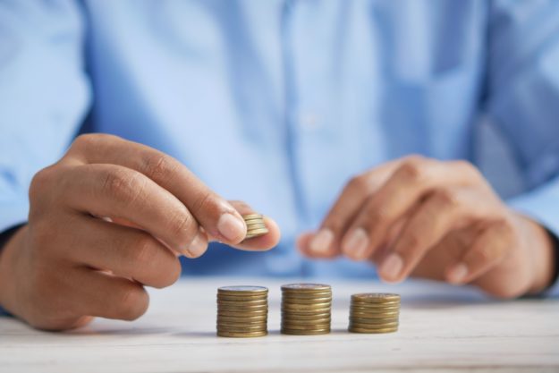 A person stacks coins on a table