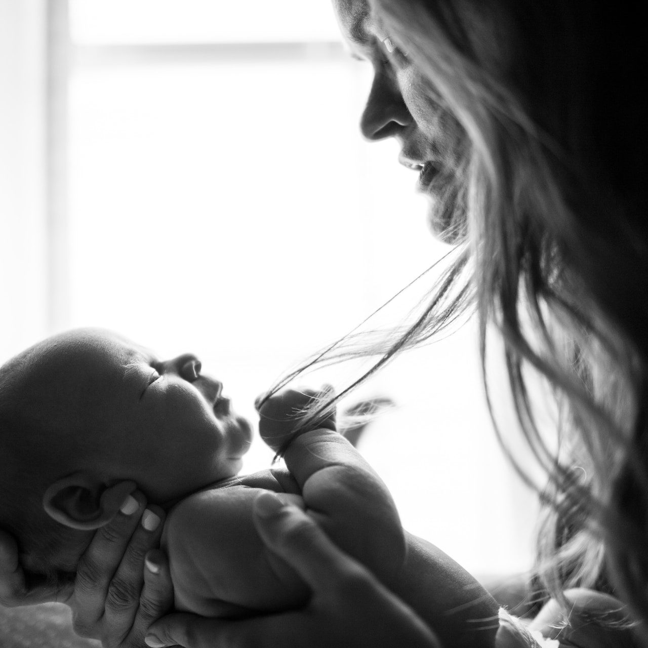 A woman holds her baby in a black and white photo.