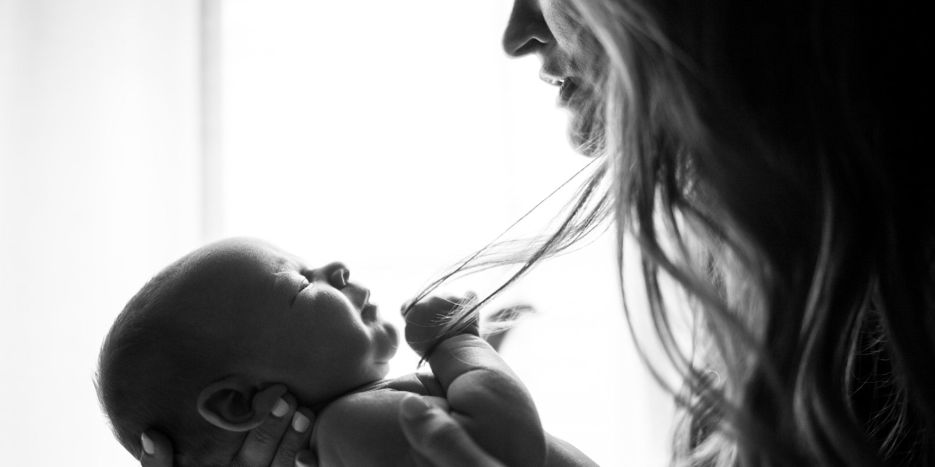 A woman holds her baby in a black and white photo.