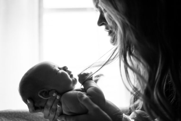 A woman holds her baby in a black and white photo.