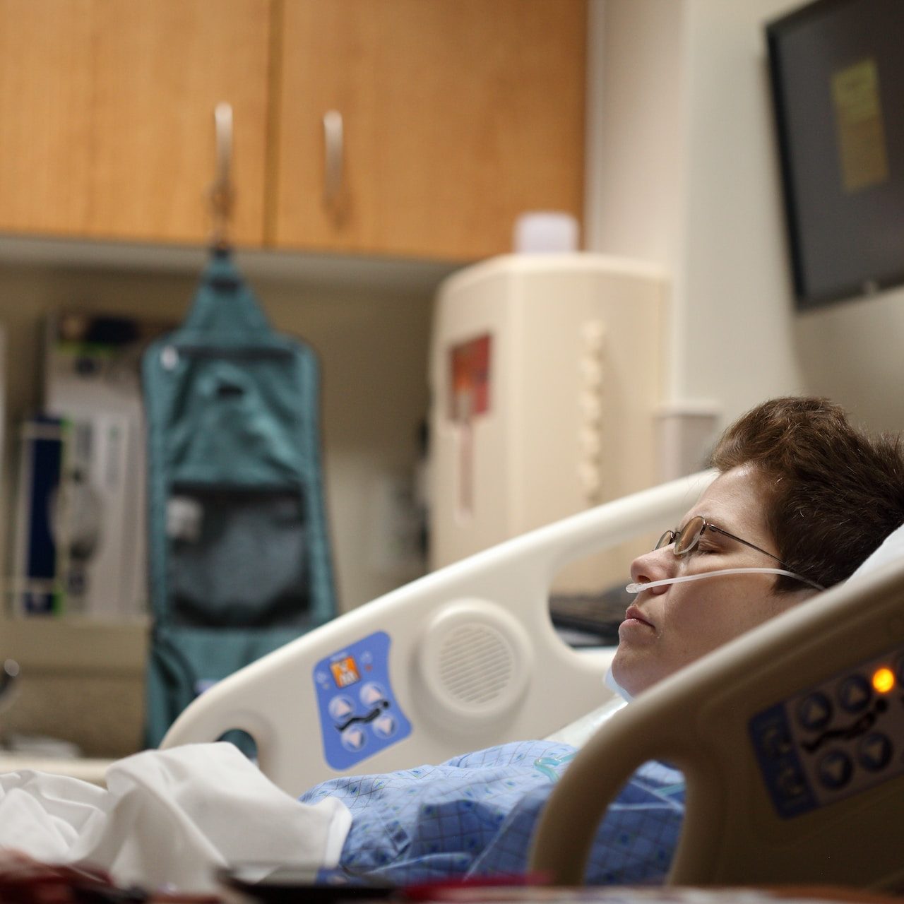 A woman sleeping in a hospital bed, breathing oxygen through a nasal cannula.