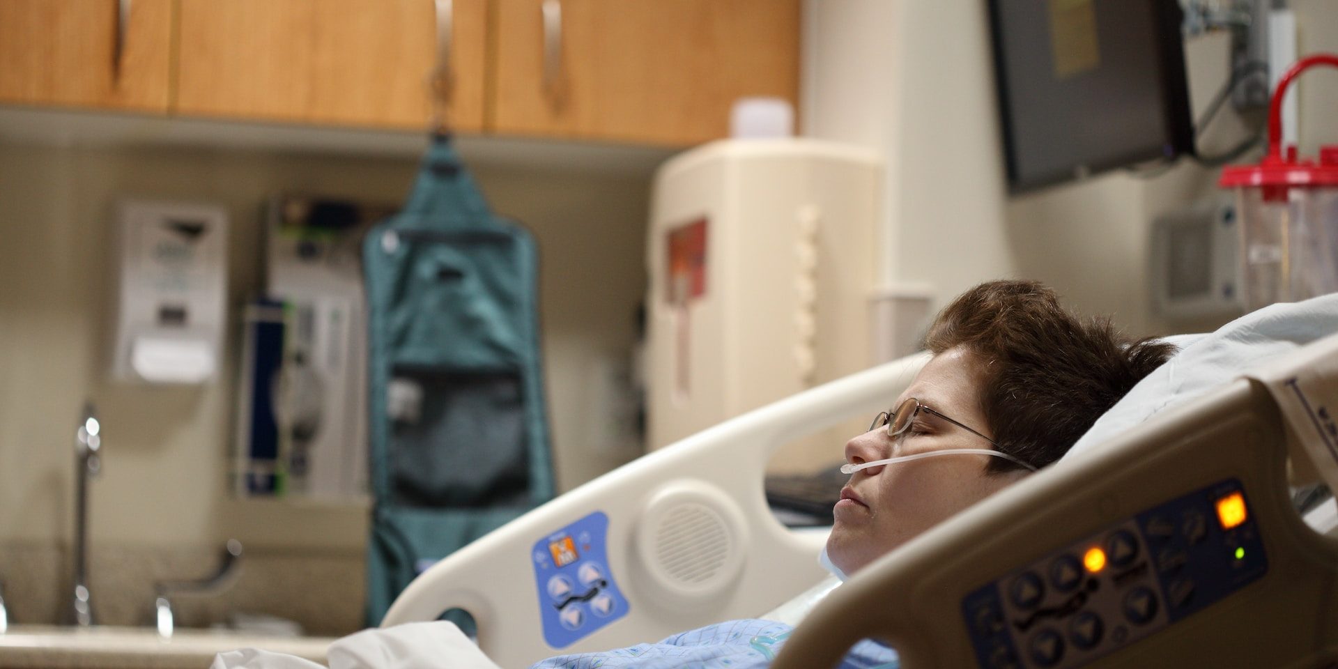 A woman sleeping in a hospital bed, breathing oxygen through a nasal cannula.