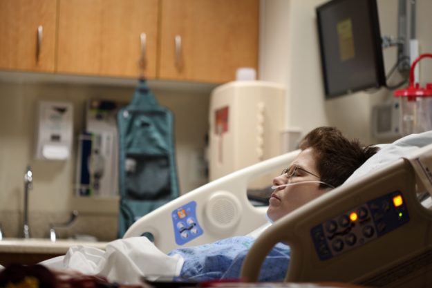 A woman sleeping in a hospital bed, breathing oxygen through a nasal cannula.