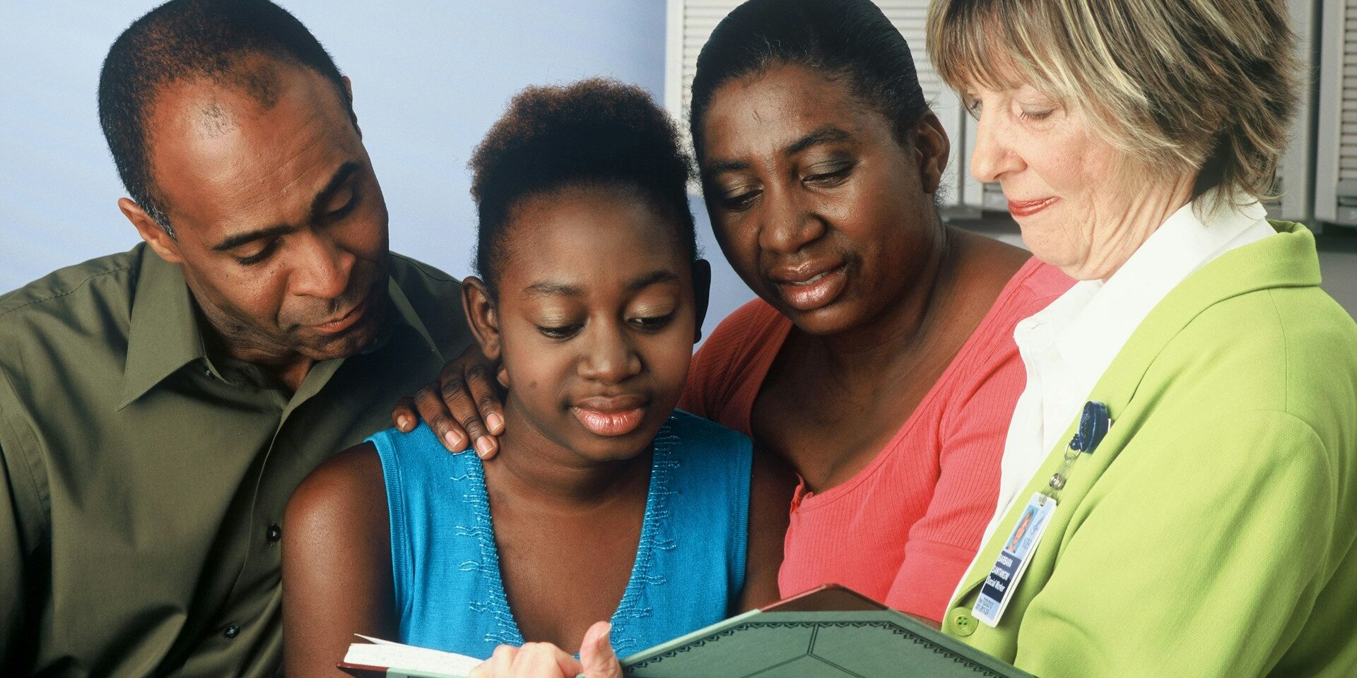 An African American female teenager and her parents consult with a female Caucasian doctor.