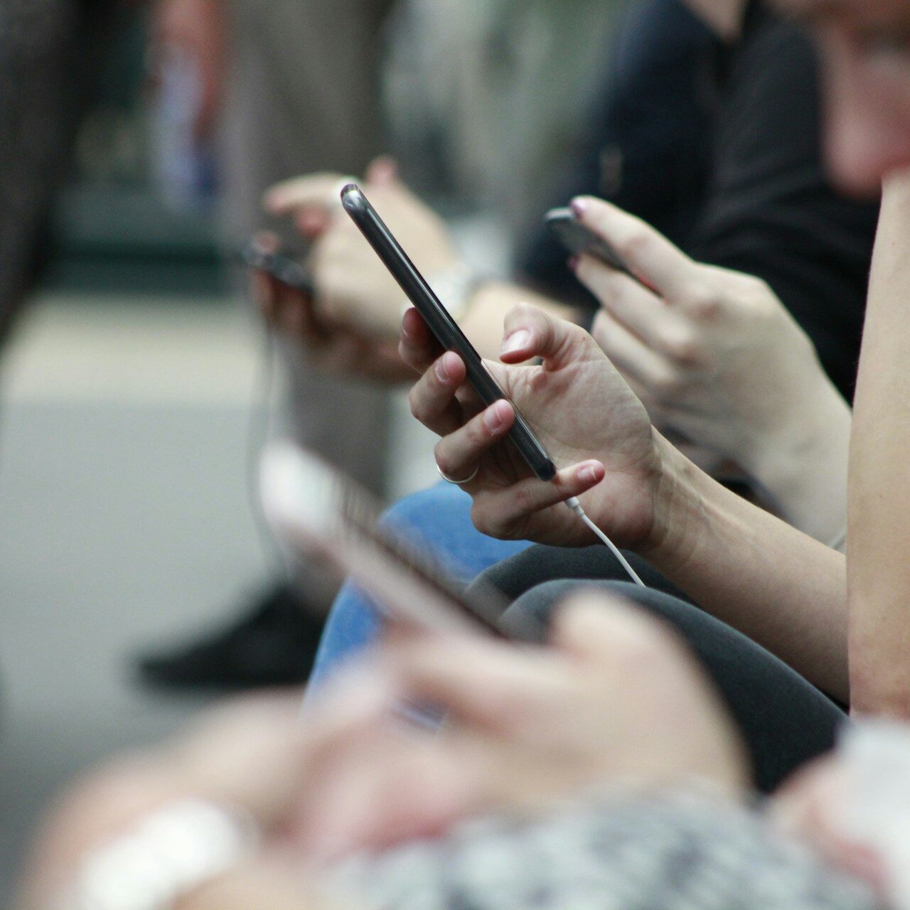 Several teens use their phones in a closeup shot of their hands.