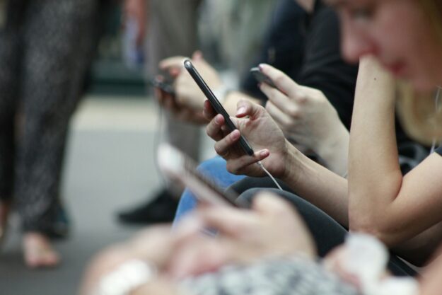 Several teens use their phones in a closeup shot of their hands.