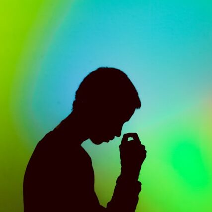 Silhouette of a man looking stressed against a blue-green background.