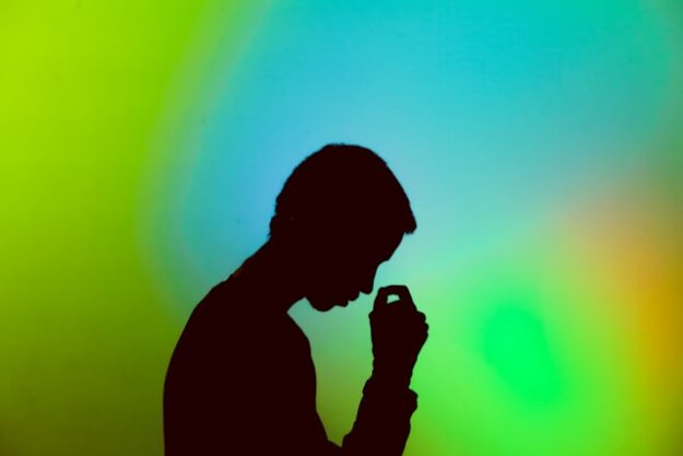 Silhouette of a man looking stressed against a blue-green background.
