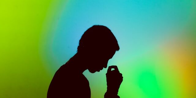 Silhouette of a man looking stressed against a blue-green background.