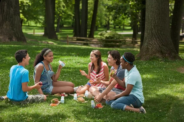 A group of young friends have an informal picnic on the grass.