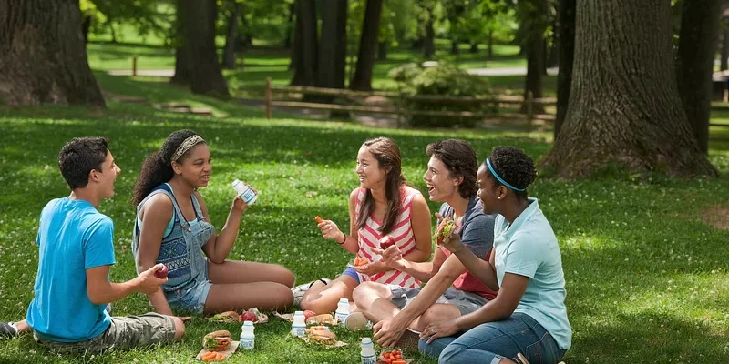 A group of young friends have an informal picnic on the grass.
