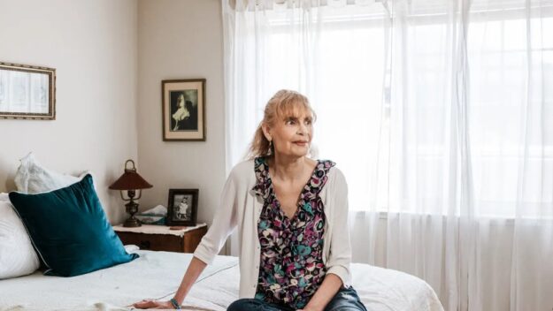 EDRC Founder Janice Bremis sits contemplatively on a bed.