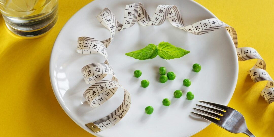 A dining plate with a handful of peas and sprig of mint, along with a tape measure.