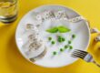 A dining plate with a handful of peas and sprig of mint, along with a tape measure.