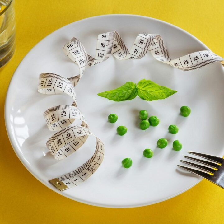 A dining plate with a handful of peas and sprig of mint, along with a tape measure.