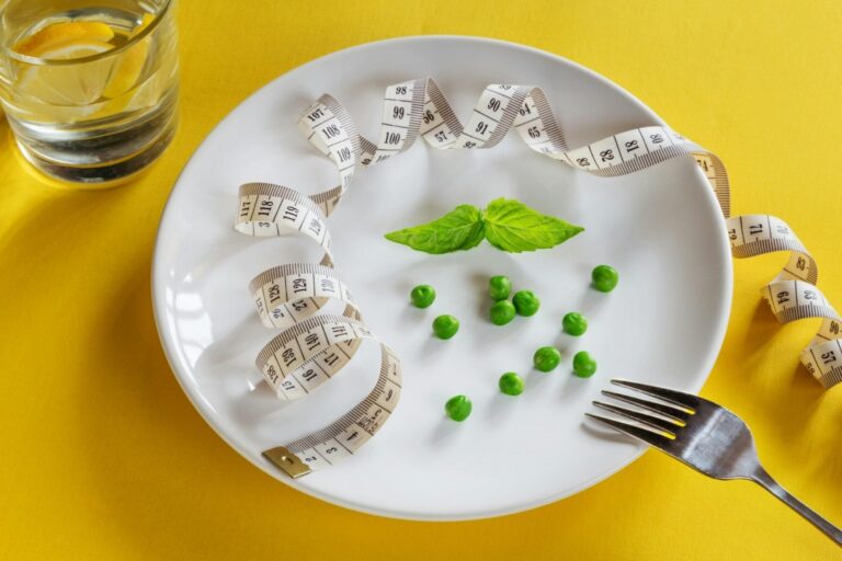 in-the-news-subthreshold-eating-disorders A dining plate with a handful of peas and sprig of mint, along with a tape measure.