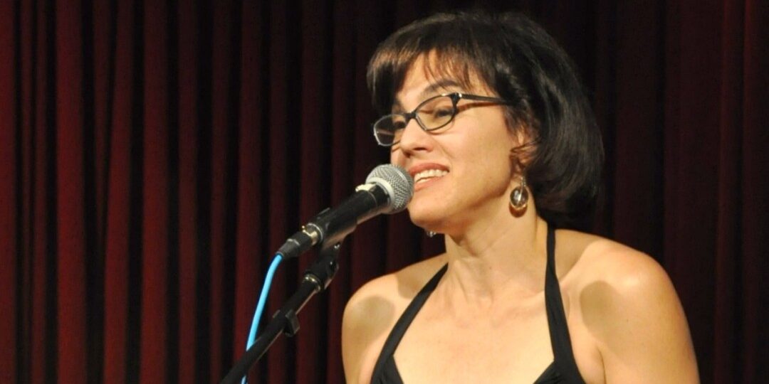 Journalist Abby Ellin on-stage speaking into a microphone.