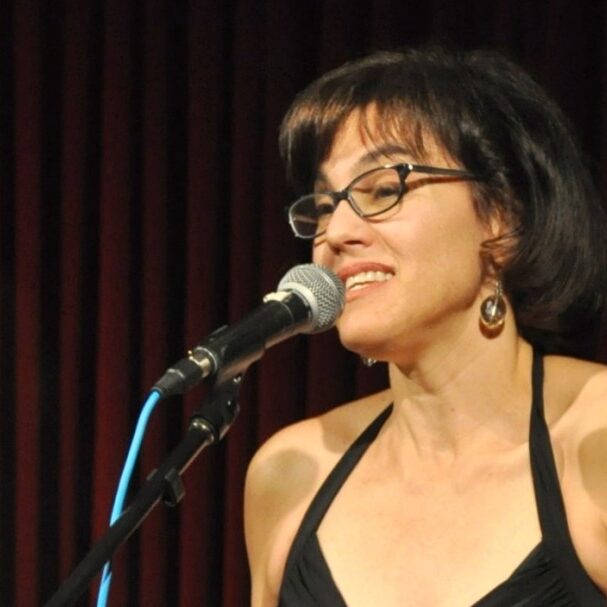 Journalist Abby Ellin on-stage speaking into a microphone.